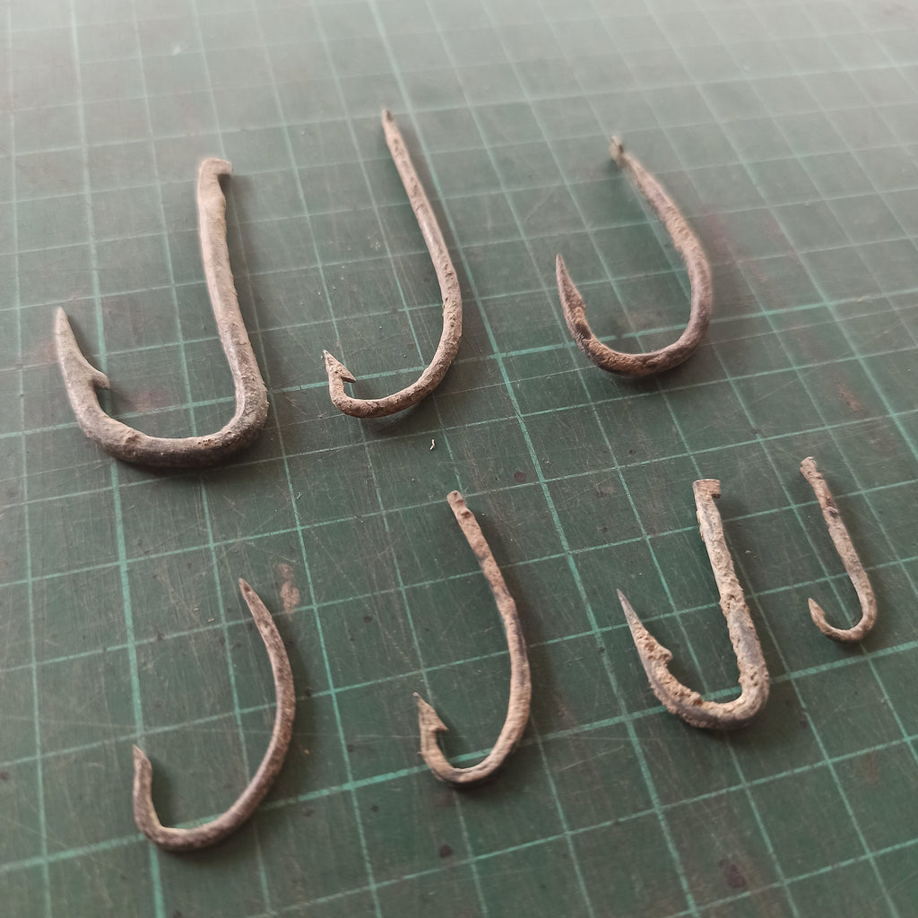 Set of rusty fishing hooks on a green cutting mat with grid lines
