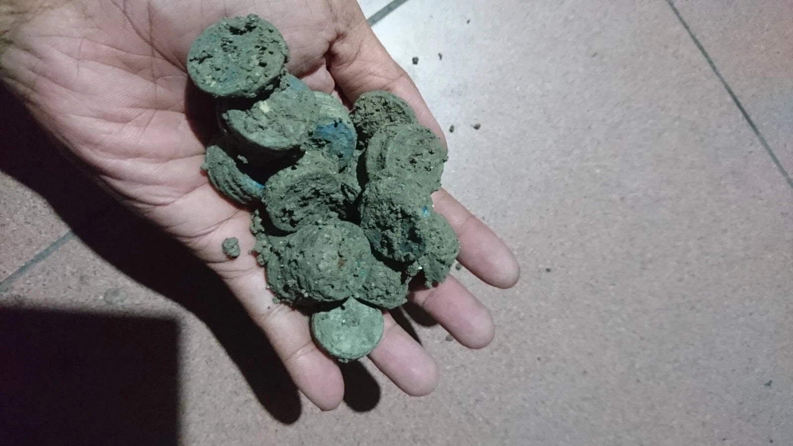 Hand holding uncleaned china coin clumps